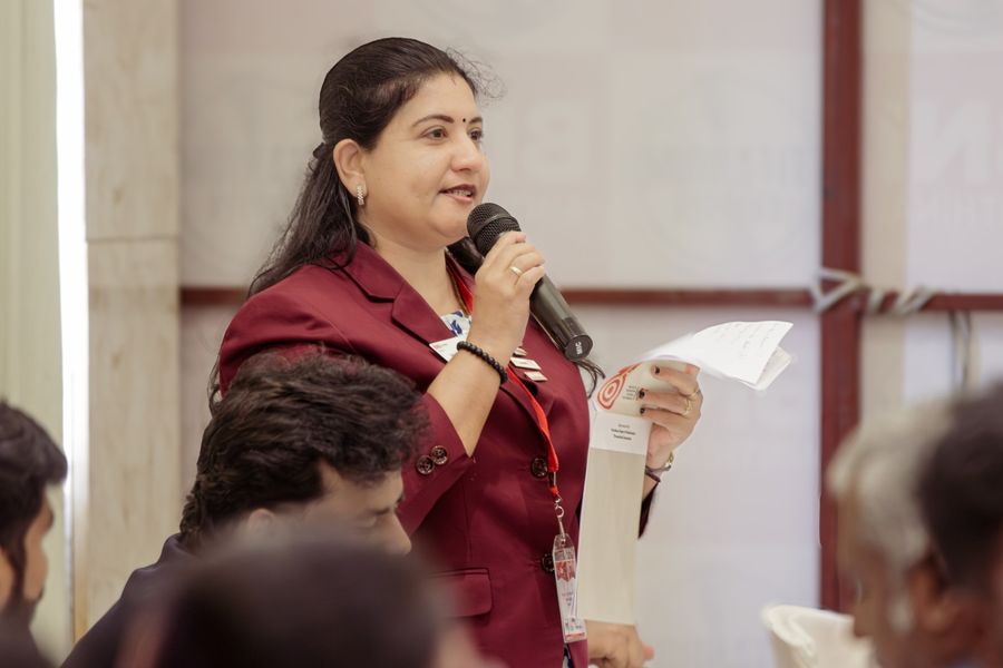 A woman member standing to address the room, microphone and notes in hand